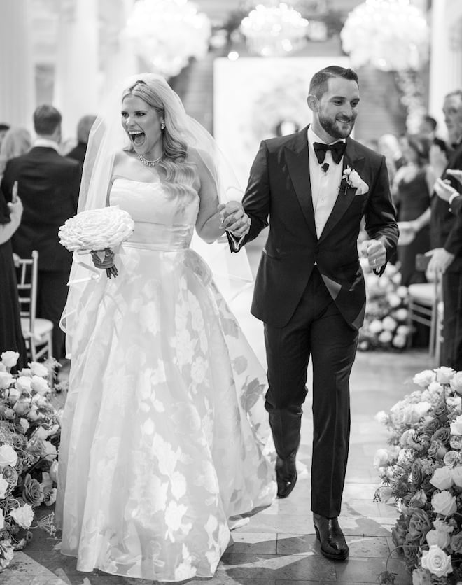 The bride and groom holding hands smiling as they walk back down the aisle. 