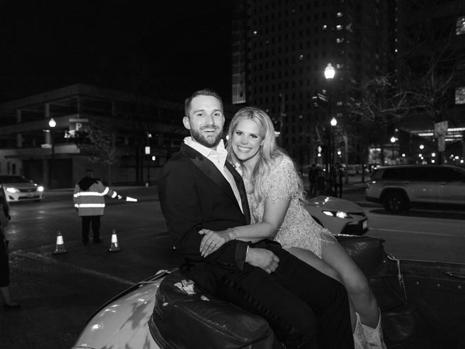 The bride and groom smiling sitting at the back of a getaway car. 