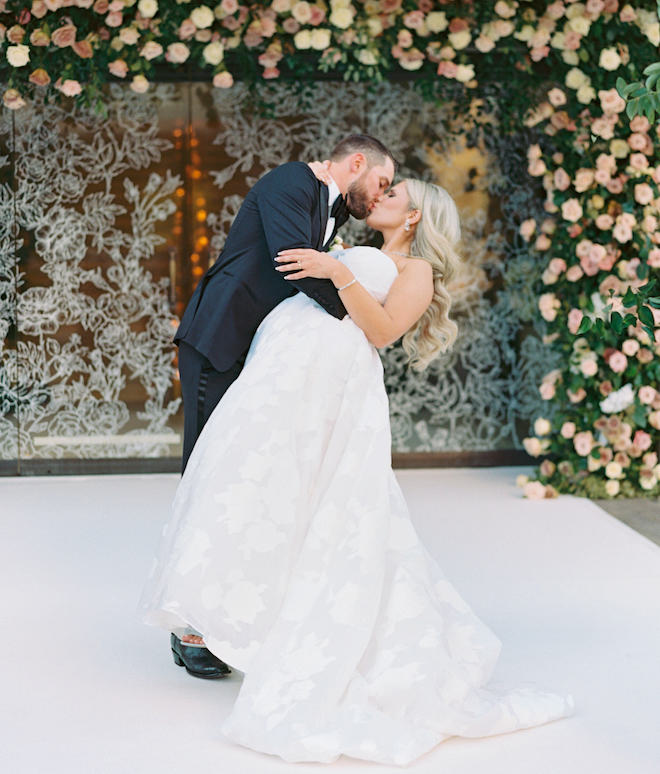 The bride and groom kissing outside the floral entryway.