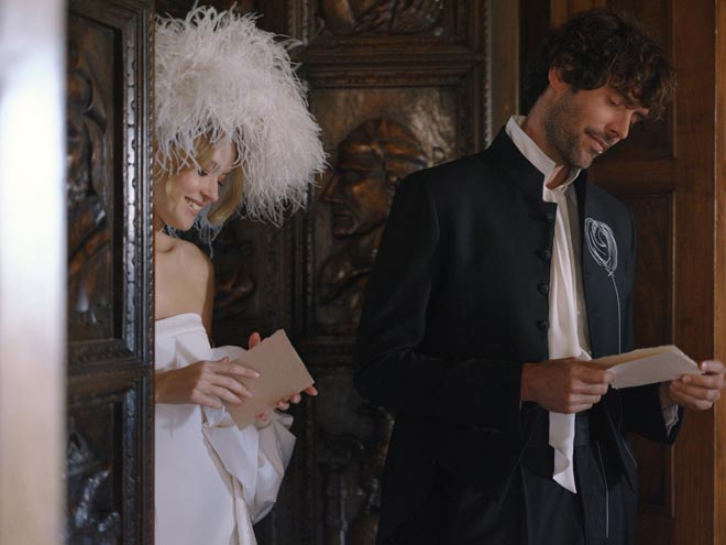 The bride and groom reading letters next to each other and smiling. 