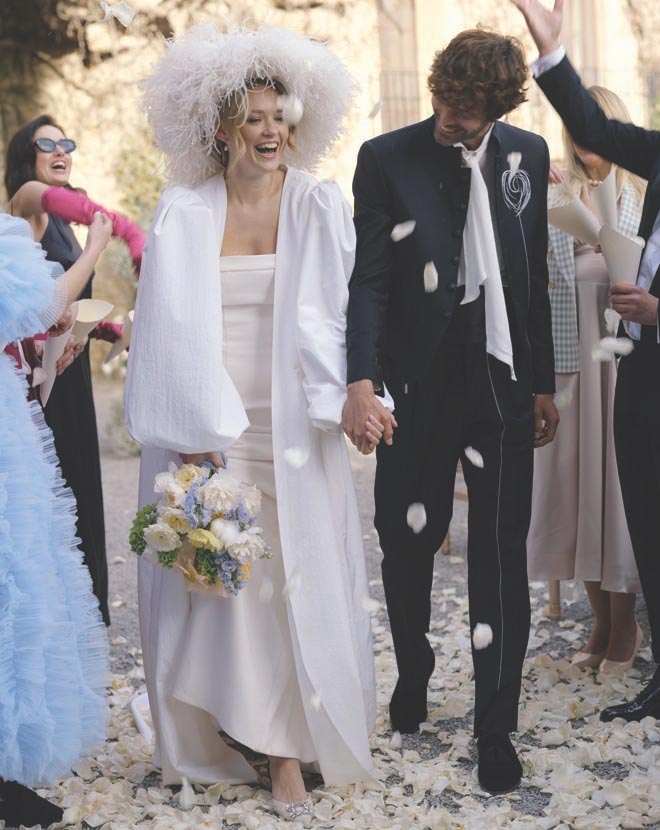 The bride and groom holding hands walking back down the aisle as guests throw rose petals at them. 