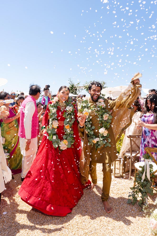 Friends and family throw flower petals as the bride and groom walk down the aisle. 