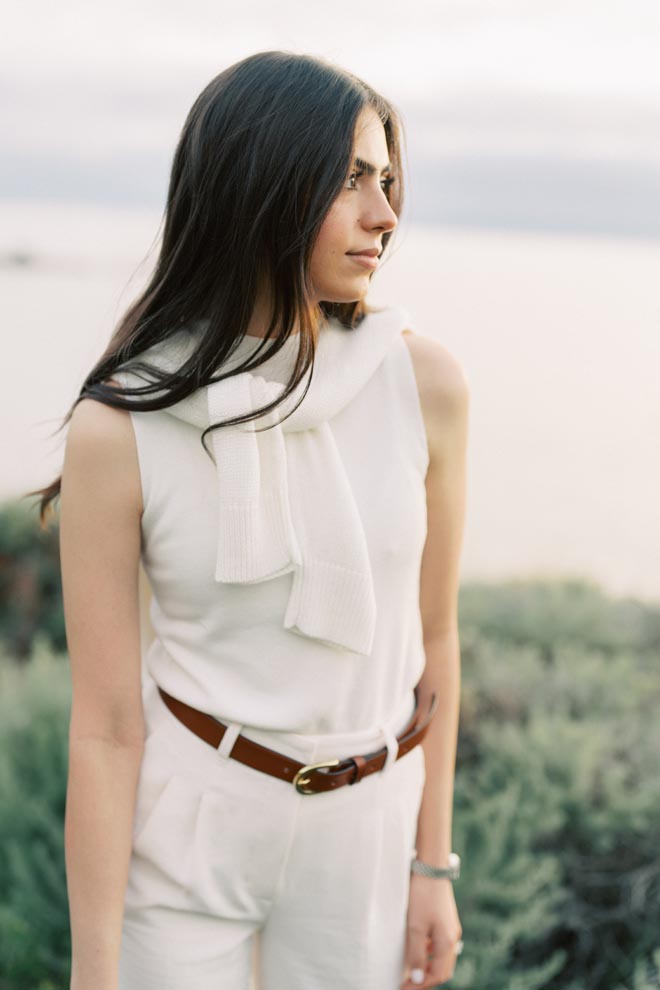 The woman stands along the California shoreline wearing preppy clothing at her engagement session with Sean Thomas Photography.