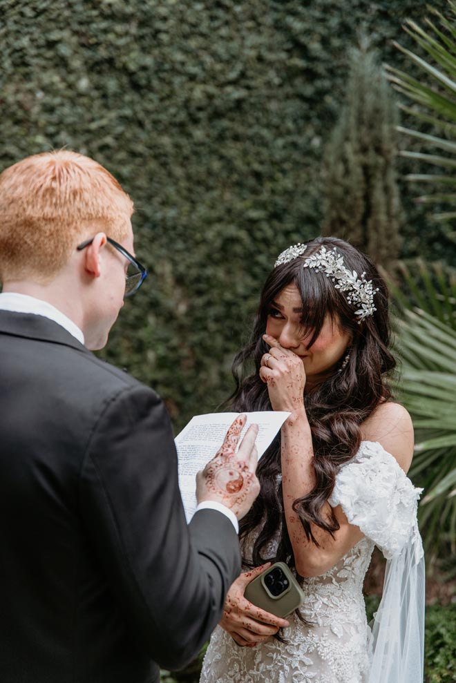 The bride holds back tears as the groom reads her his handwritten vows.