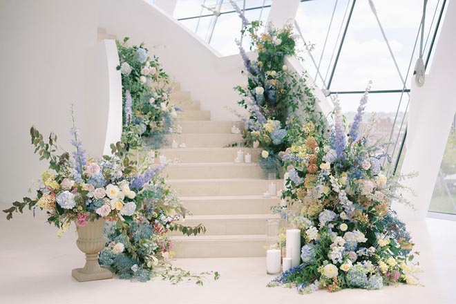 A staircase decorated with blue, white and purple florals and candlelight. 