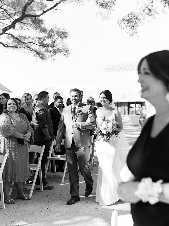 The bride's father walks her down the aisle at her French blue wedding in Houston.