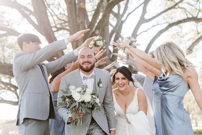 The bride and groom hold hands as they run through their cheering wedding party.