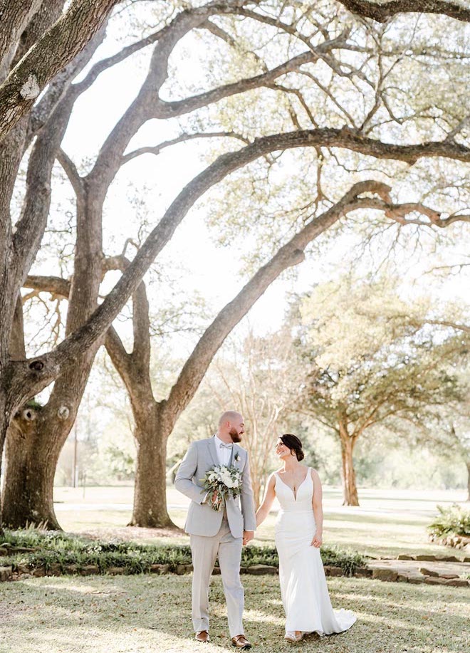 The bride and groom hold hands at their rustic French blue wedding in the countryside.