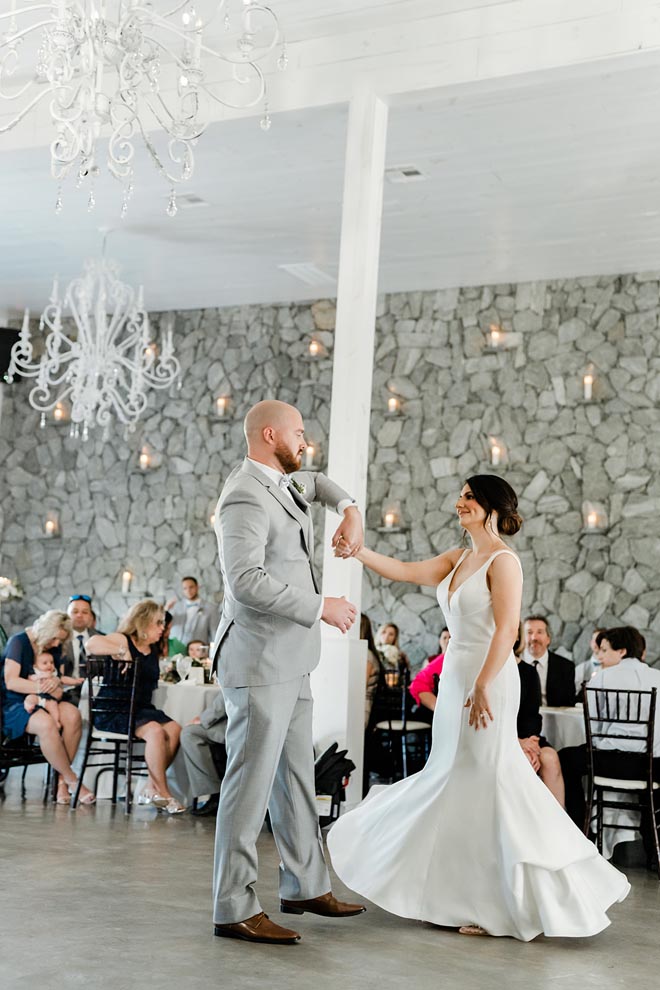 The bride and groom dance at their wedding reception as guests watch.