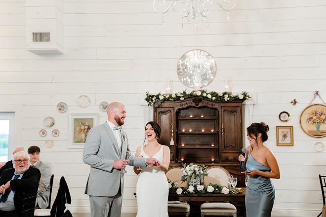 The bride and groom share a laugh while one of the bridesmaids gives a speech at the French blue wedding reception.