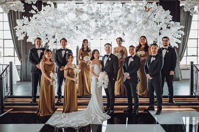 The bride and groom pose with their wedding party on the alter of their monochromatic wedding at The Astorian. 