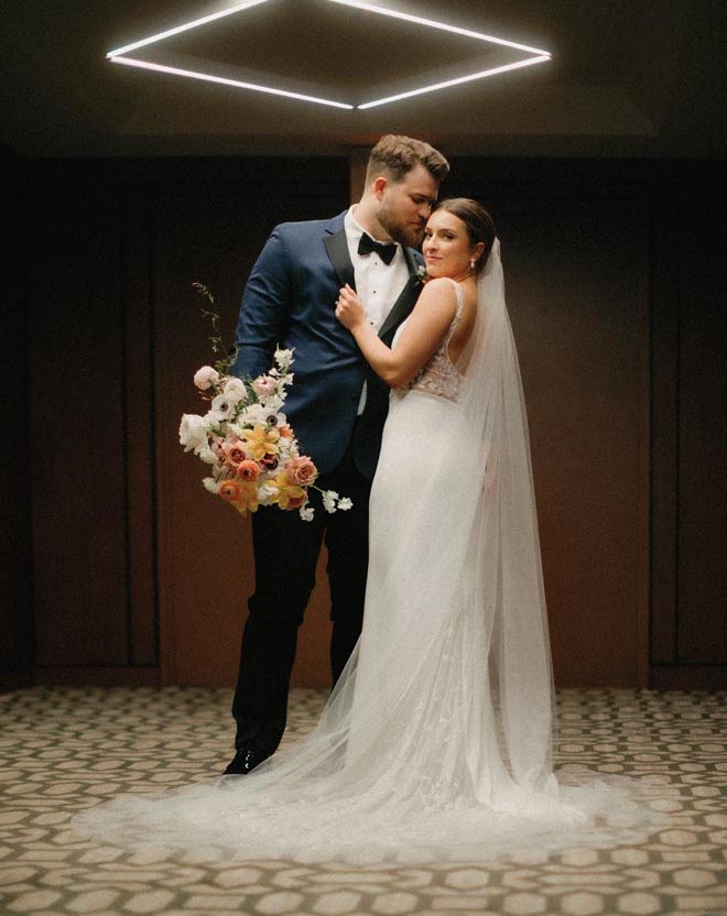 The bride and groom pose in the Omni Houston Hotel ballroom at their springtime garden wedding. 