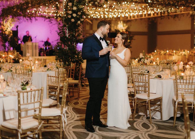 The bride and groom cheers with a glass of champagne at their springtime garden wedding. 