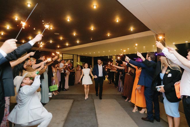 The bride and groom hold hands as they walk through their sparkler send-off. 