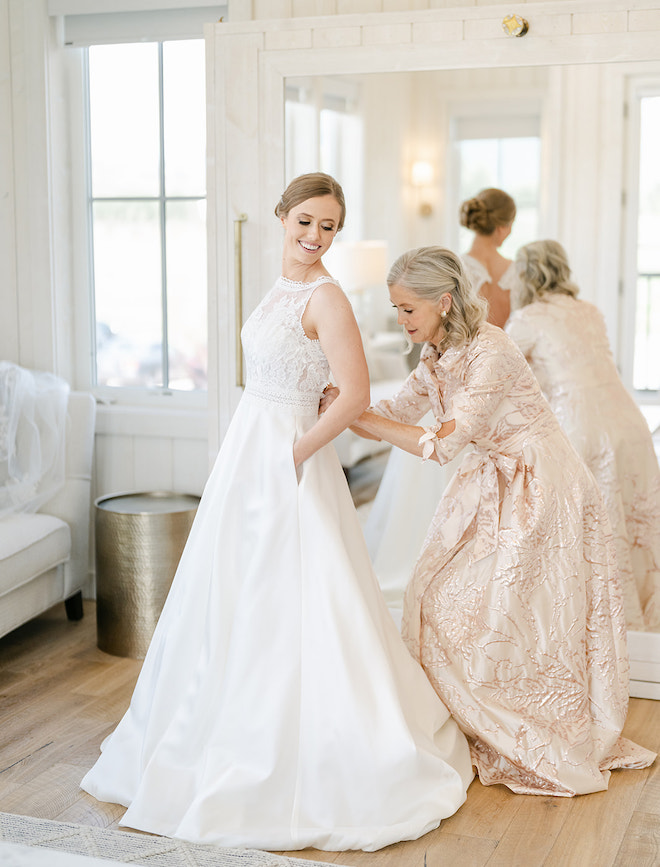 The bride's mother helping the bride button her dress. 