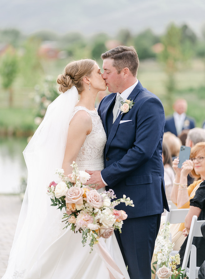 The bride and groom kissing as they walk down the aisle. 