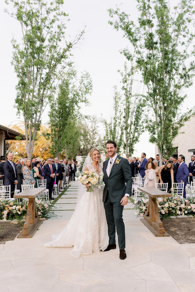 The bride and groom smile at the end of the aisle after their outdoor wedding ceremony.