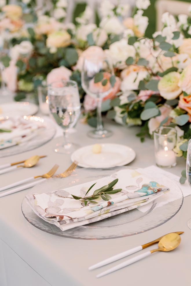 Sage, peach and orange colored flowers and linens decorate the outdoor wedding reception.