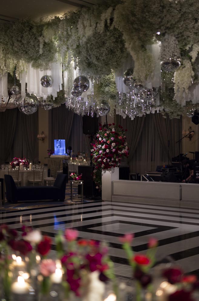 Greenery and disco balls hangover the black and white dance floor at the New Year's Eve wedding. 