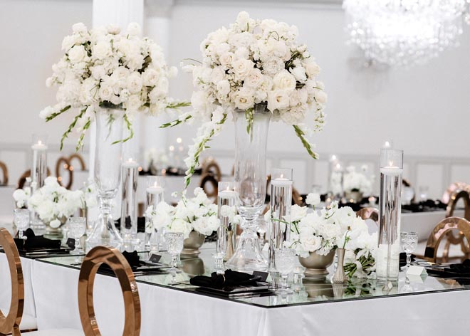 Pillar candles and floral centerpieces decorate the reception tables at the wedding venue, Sans Souci Ballroom.