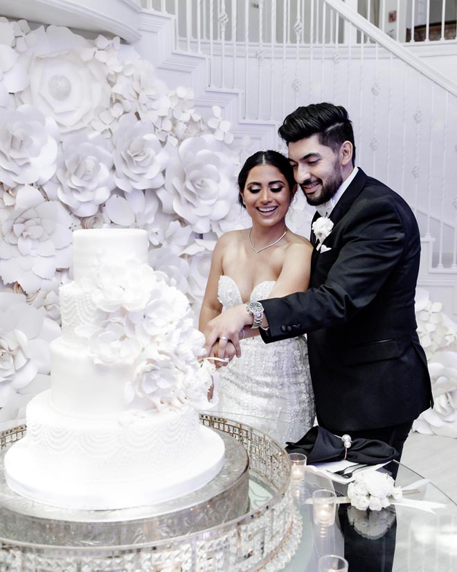 The bride and groom cut into their wedding cake at their reception.