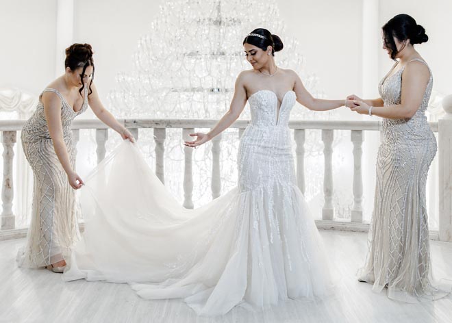 The bridesmaids help the bride and adjust the train on her wedding dress. 