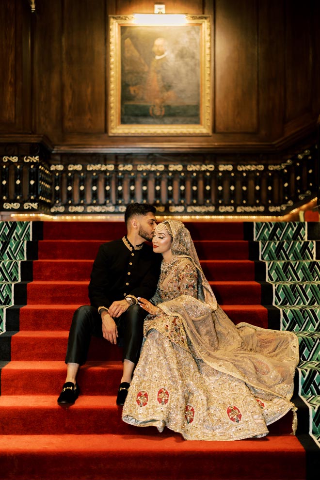 The bride and groom sit on the staircase at the Grand Galvez for their pastel Gulf Coast wedding. 