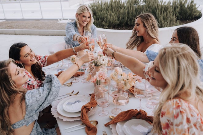 A bride and five bridesmaids clinking their champagne glasses. 