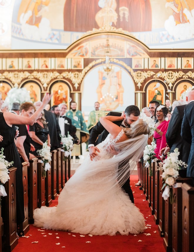 The bride and groom kissing in the middle of the aisle at the church. 