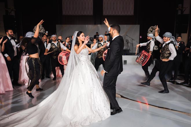 The bride and groom dance to live drummers at their glamorous ballroom reception in Houston.