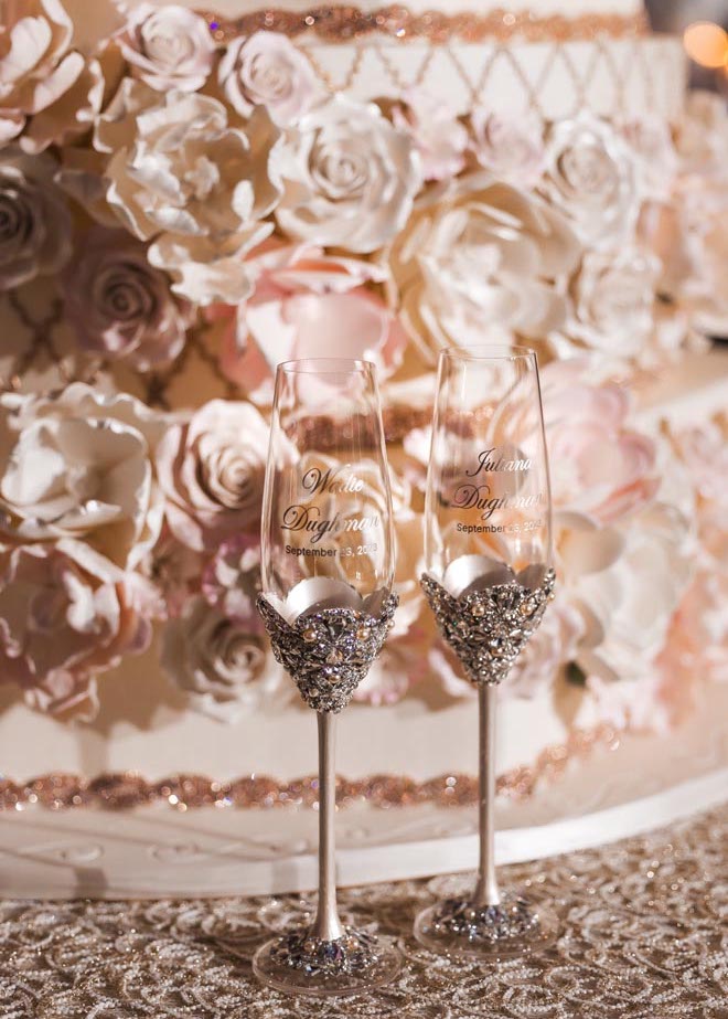 Champagne flutes with the bride and grooms names sit in front of the wedding cake.