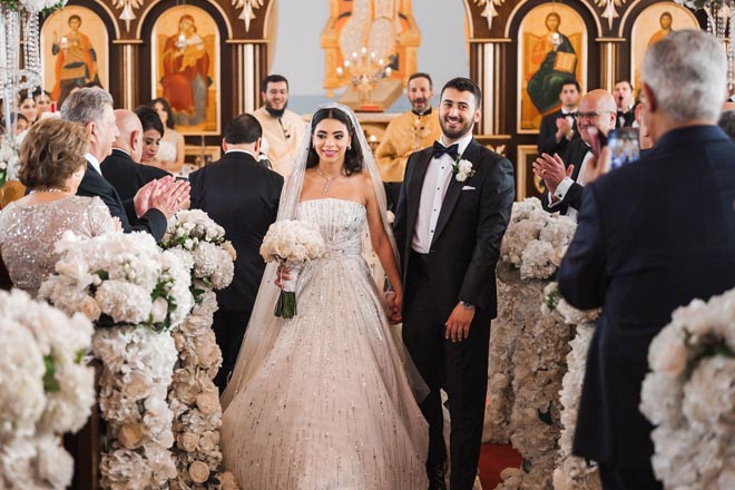 The bride and groom hold hands as they walk down the aisle.