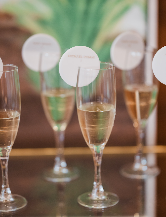 Champagne with a name tag and table number on the rim.