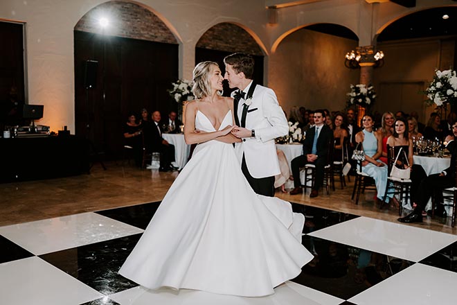 The bride and groom dancing on the black and white checkered dance floor. 