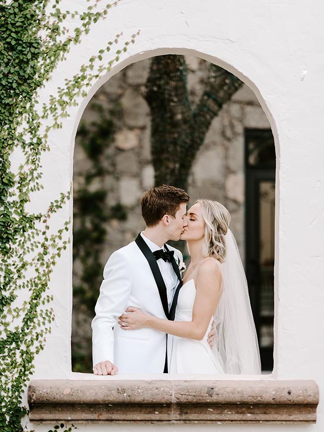 The bride and groom kissing in an archway of The Bell Tower on 34th. 