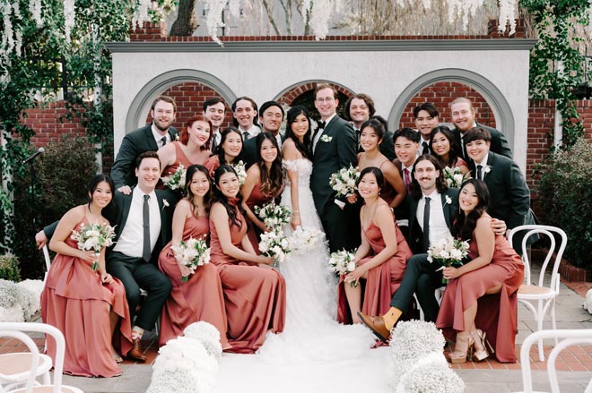 The bride and groom smile with their wedding party at the wedding ceremony venue in Houston.