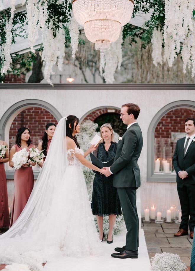 The bride and groom hold hands at the alter during their outdoor wedding ceremony.