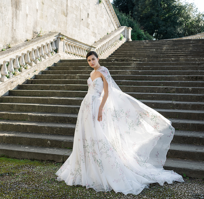 A strapless wedding dress with a small blue, green and pink floral print with a matching cape. 