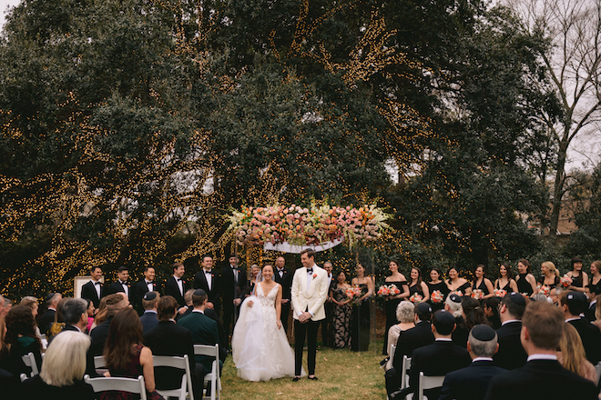 A bride and groom walking back down the aisle in front of the oak tree at The Houstonian. 