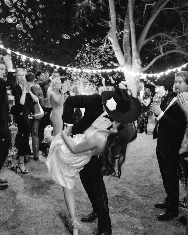 The groom dips the bride and gives her a kiss. 