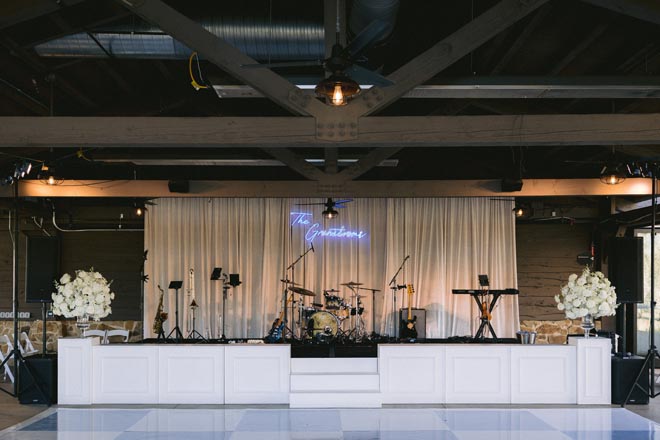 A blue and white checkered dance floor and neon sign decorate the reception space. 