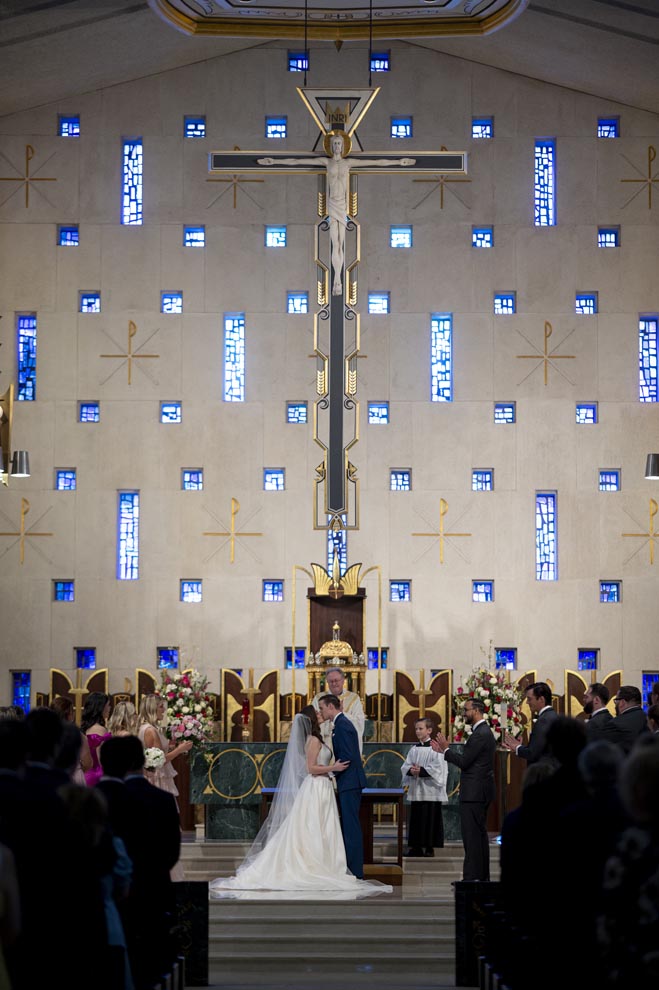 The bride and groom share a kiss on the altar at their church ceremony. 