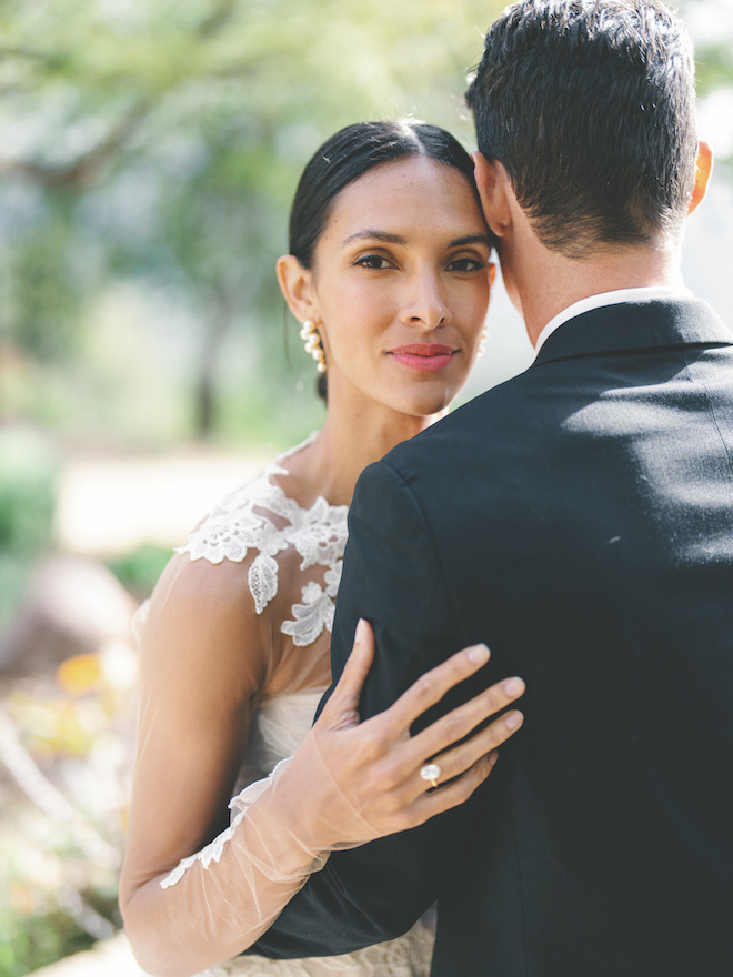 The bride smiling while hugging the groom. 