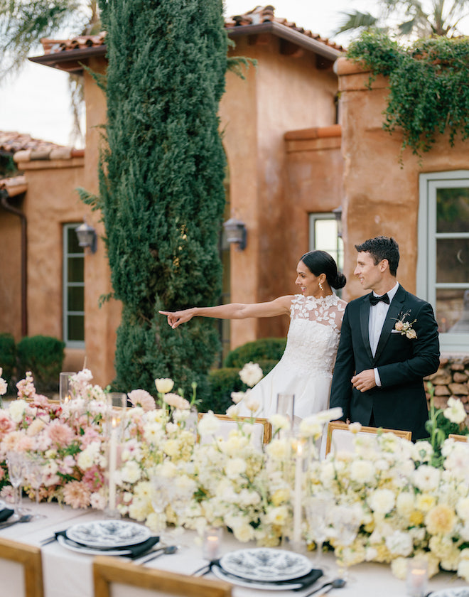 The bride pointing while standing next to the reception table. 