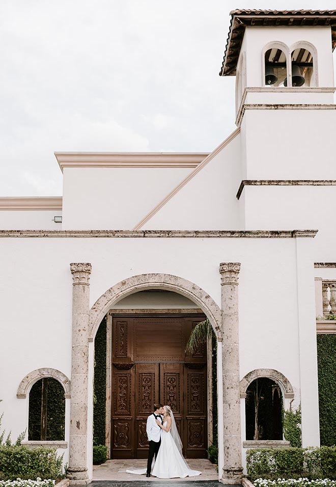 The bride and groom kissing in front of The Bell Tower on 34th. 