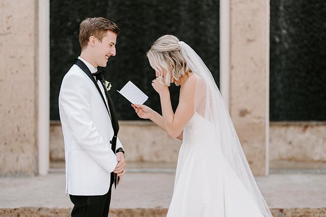 The bride and groom laughing while privately reading their vows to each other. 