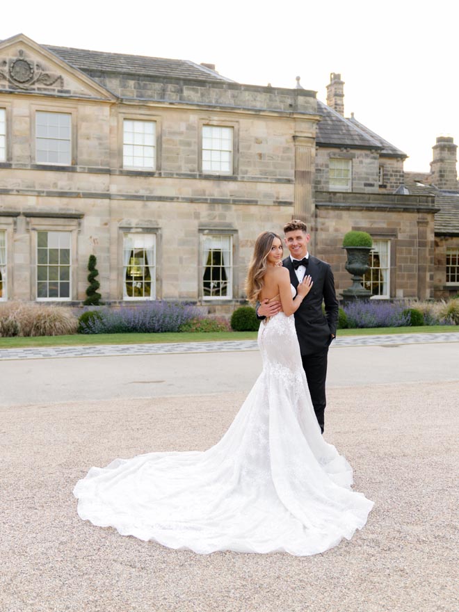 The bride and groom hug outside their wedding venue, Grantley Hall.