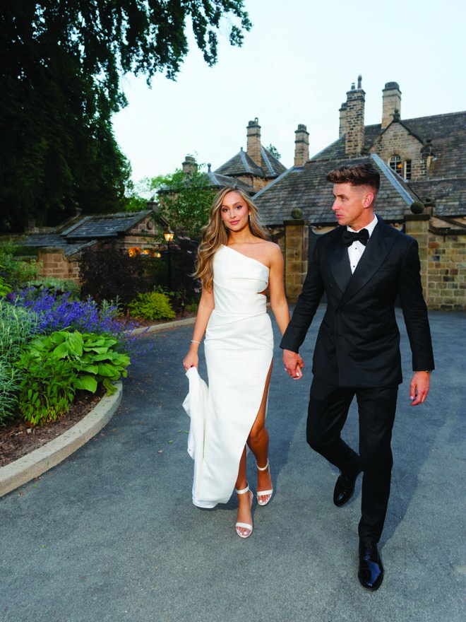 The bride and groom hold hands as they walk to their wedding reception. 