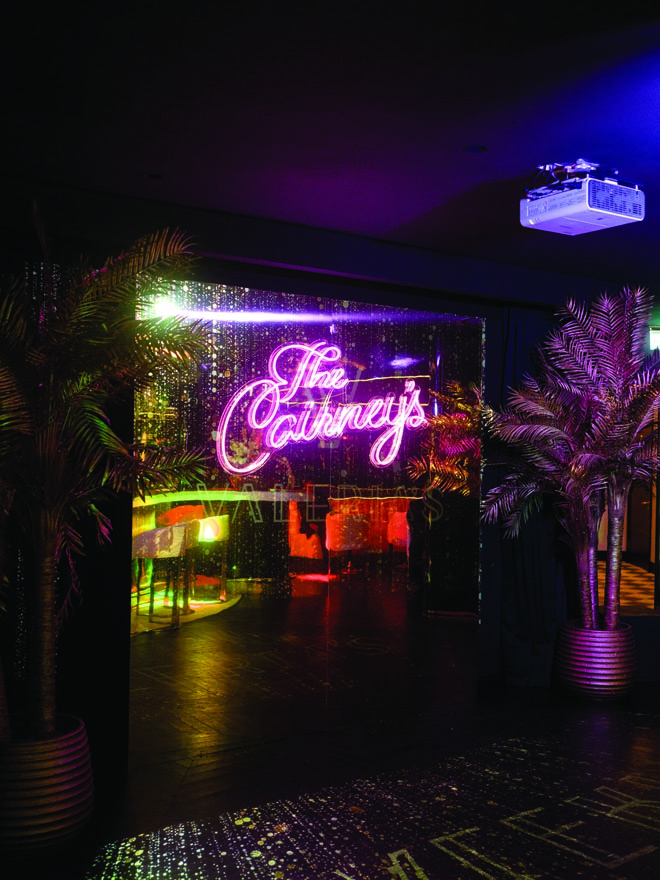 A neon sign with the bride and groom's last name is lit up at the wedding reception.