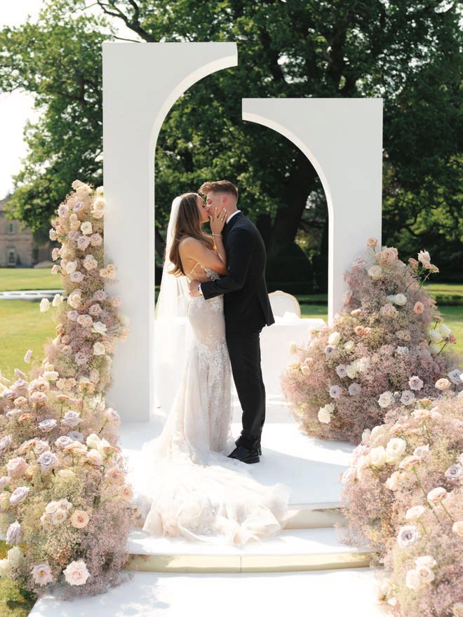 The bride and groom kiss on the altar at their storybook wedding in England.